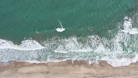 Little-waves-shore-breaking-a-sandy-beach-blue-water-near-Montpellier-aerial